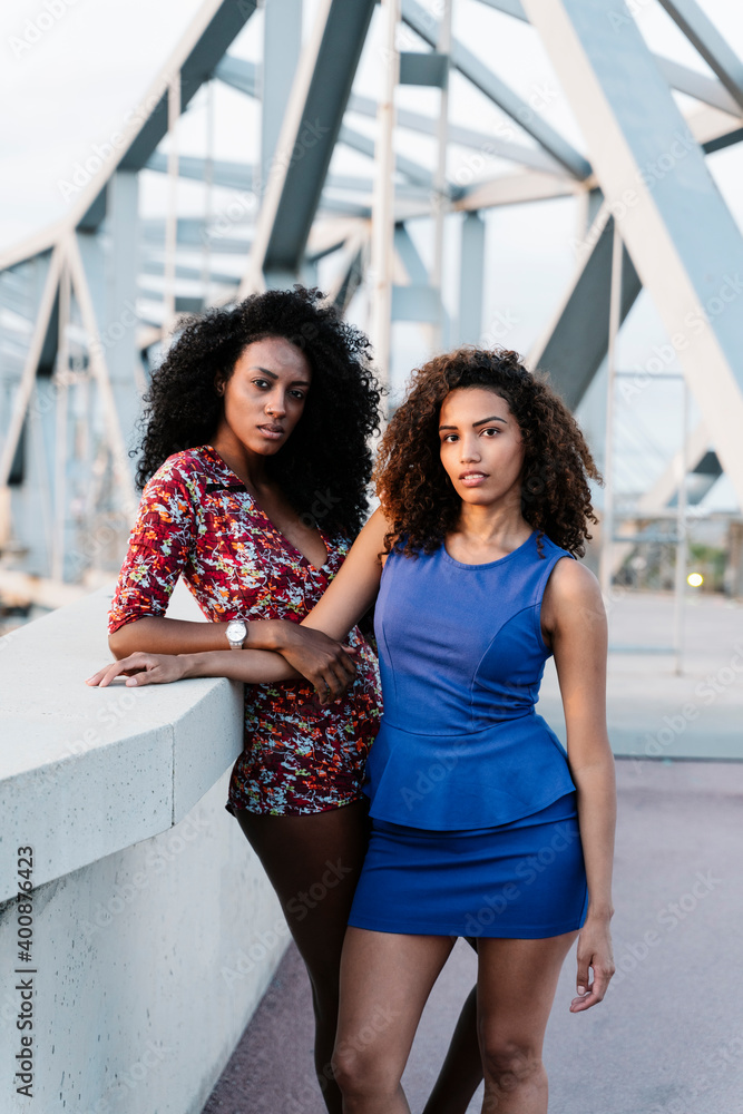 Confident young female friends standing on bridge Confident young female friends standing on bridge