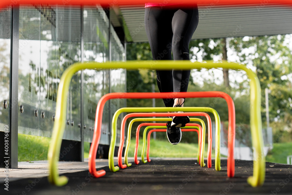 Athlete running over small hurdle by training ground Athlete running over small hurdle by training ground