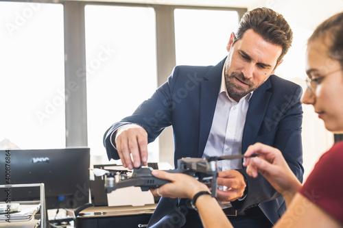 Businessman examining quadcopter with colleague at office
