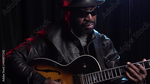 Close up Black Jazz musician soulfully playing guitar in dark studio