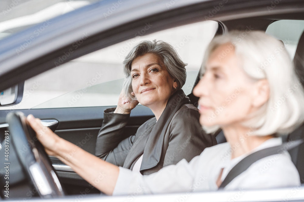 Businesswoman smiling while sitting by female colleague driving car in city Businesswoman smiling while sitting by female colleague driving car in city