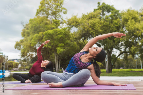 Active women practicing yoga against trees at park