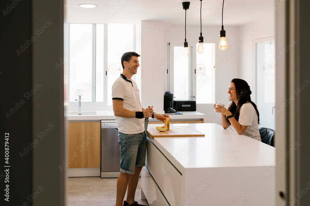 Couple laughing while cutting fruit in kitchen at home Couple laughing while cutting fruit in kitchen at home