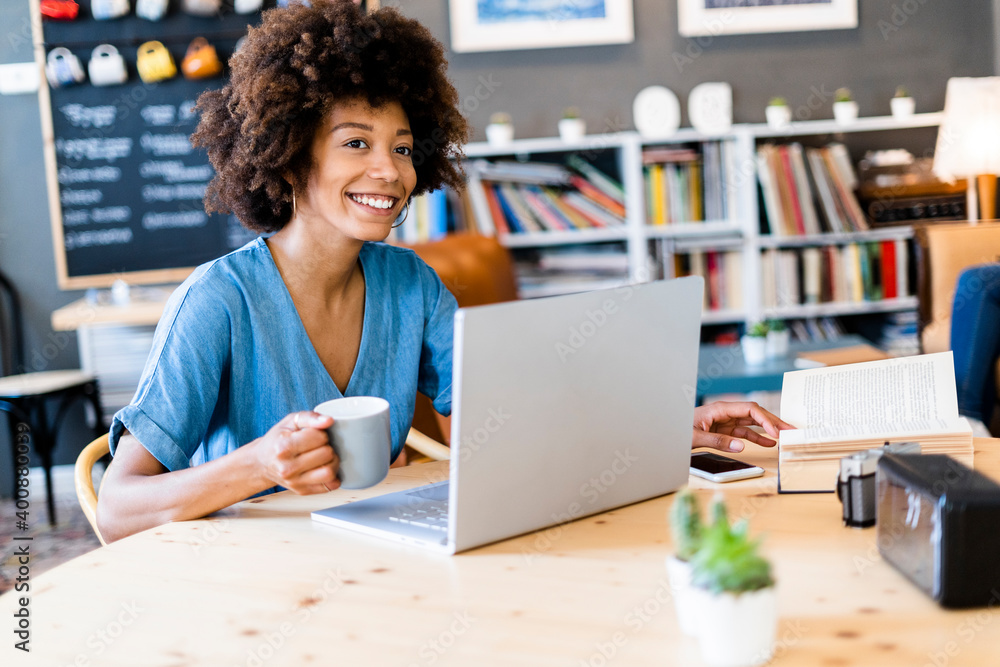 Thoughtful woman holding coffee mug while sitting with laptop at cafe table Thoughtful woman holding coffee mug while sitting with laptop at cafe table