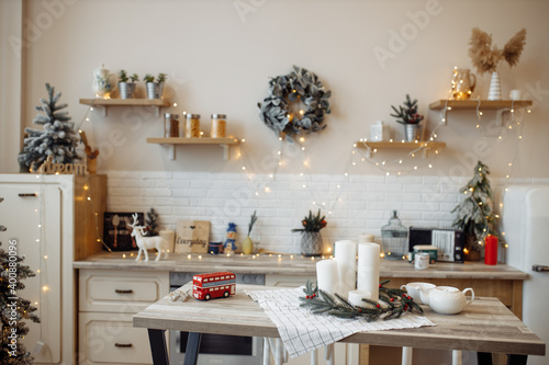 Photo of decorated before christmas holidays kitchen with xmas tree wreath wooden decor electrical lights candles cozy interior