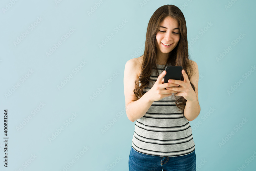 Caucasian woman is happy and sending a text on her smartphone Caucasian woman is happy and sending a text on her smartphone