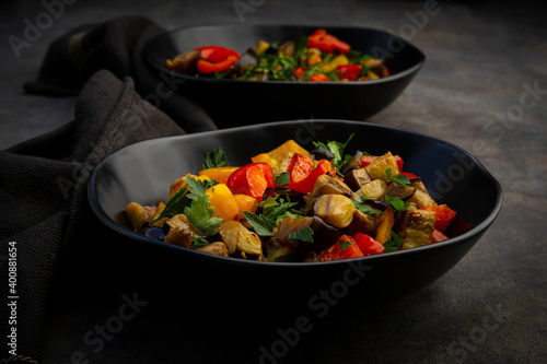 Two bowls of¬†stir-fried¬†vegan salad with eggplants, paprika and parsley photo
