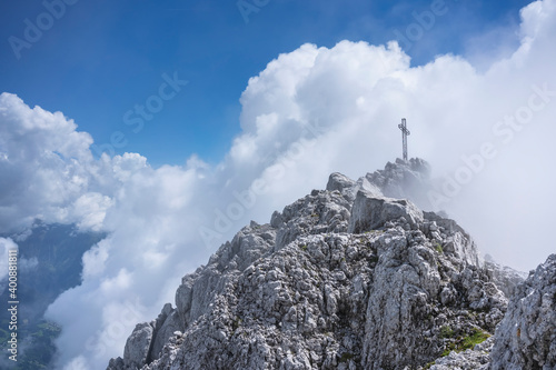 Low angle view of religious cross on mountain top against cloudy sky, Bergamasque Alps, Germany photo