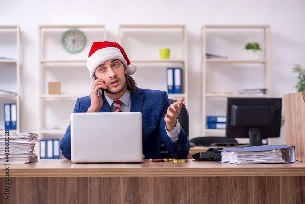 Young male employee working in the office at Christmas Eve Young male employee working in the office at Christmas Eve