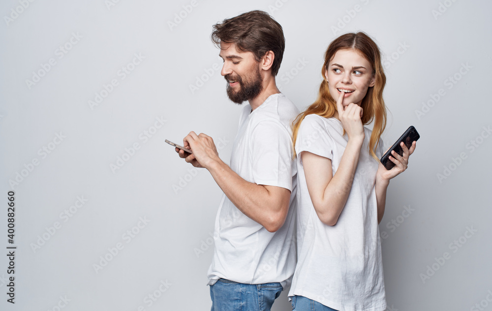 young couple in white t-shirts with phones in their hands communication internet lifestyle young couple in white t-shirts with phones in their hands communication internet lifestyle