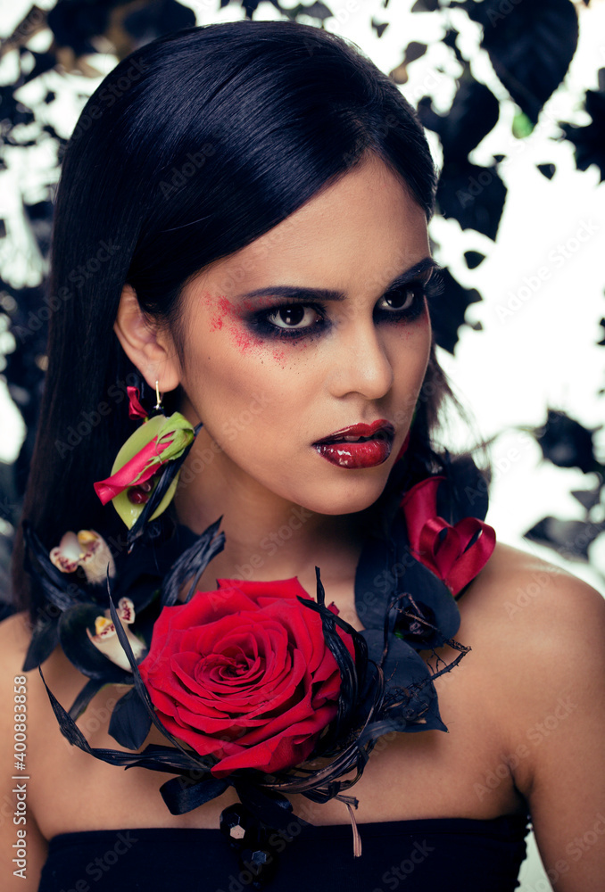 pretty brunette woman with rose jewelry, black and red, bright make up a vampire closeup red lips pretty brunette woman with rose jewelry, black and red, bright make up a vampire closeup red lips