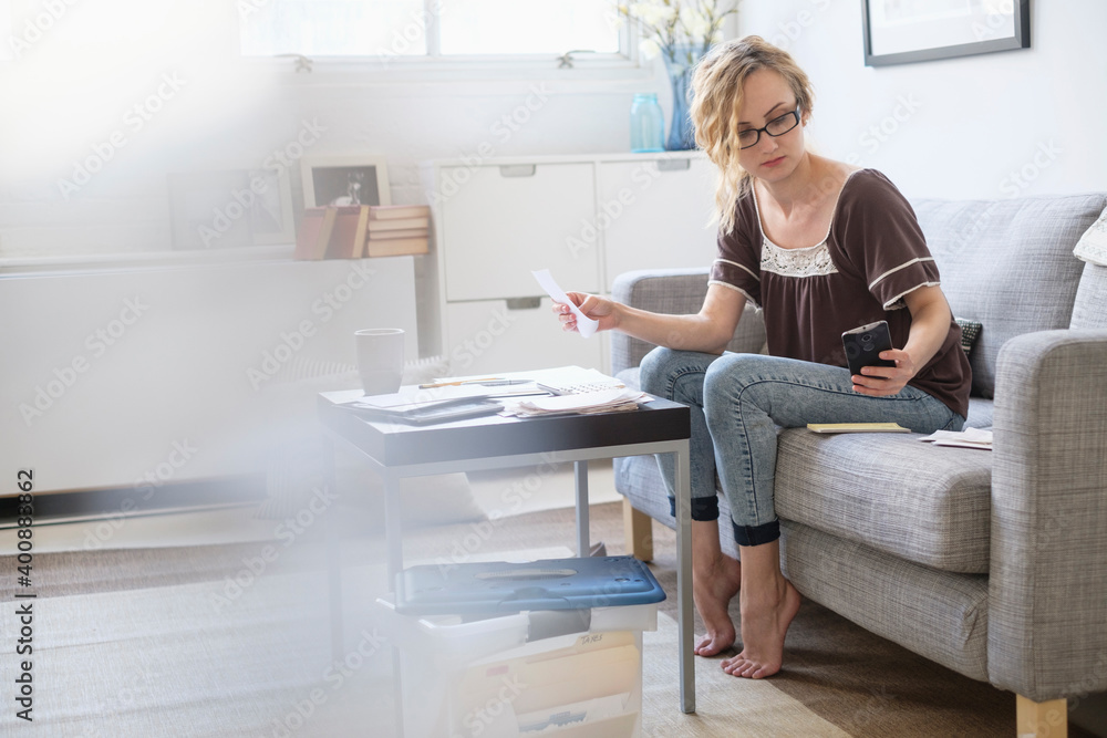Woman sitting in living room and paying bills using electronic banking Woman sitting in living room and paying bills using electronic banking