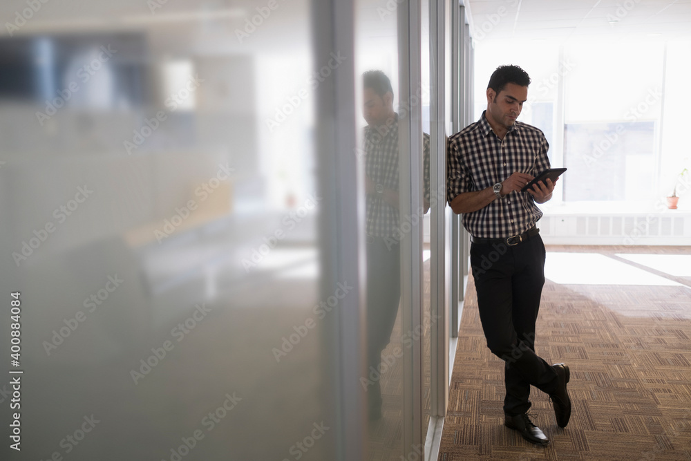 Young man standing in corridor with digital tablet Young man standing in corridor with digital tablet