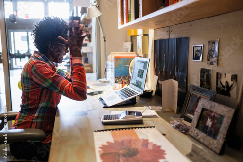 Woman gesturing in front of laptop in office