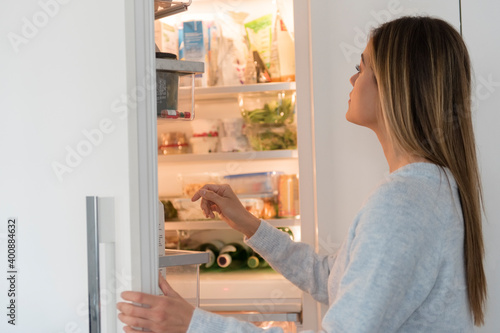 Young woman looking into refrigerator