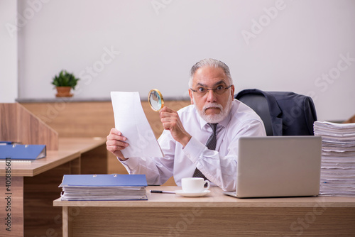 Old male employee reading paper in the office