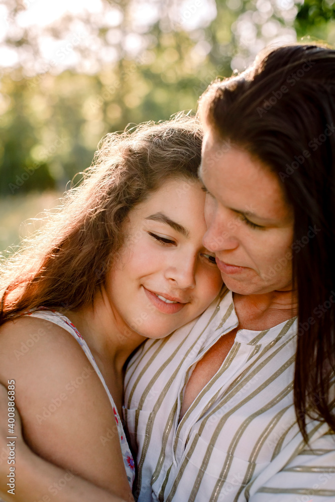 Smiling mother talking to daughter while embracing in yard Smiling mother talking to daughter while embracing in yard