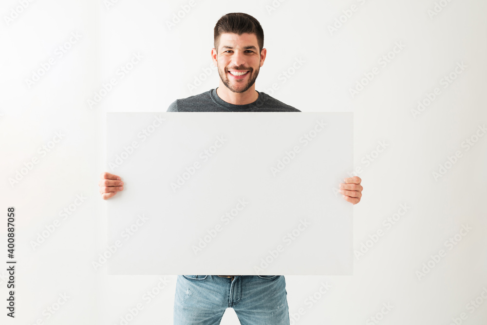 Good-looking young man holding a white blank sign Good-looking young man holding a white blank sign
