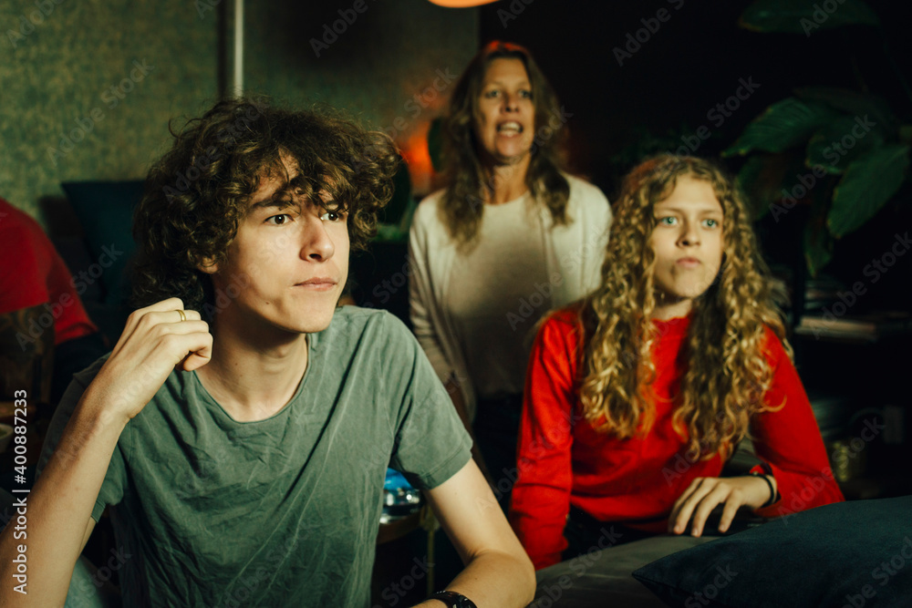 Male teenager by sister watching sports at night Male teenager by sister watching sports at night