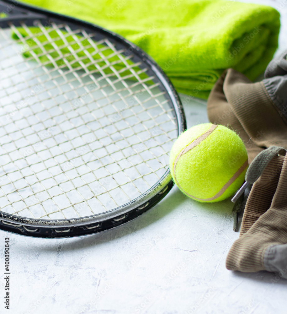 a tennis racket with a ball, a towel and shorts for training lie on a light background, the concept of sports