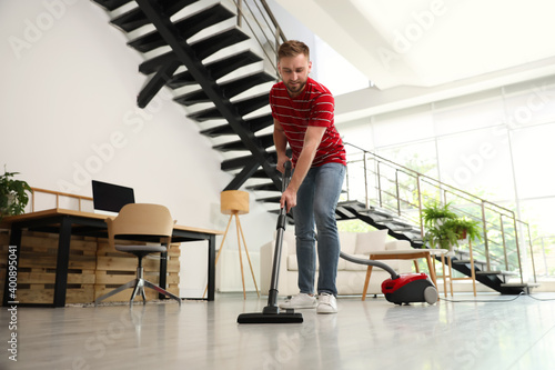 Wallpaper Mural Young man using vacuum cleaner in living room Torontodigital.ca