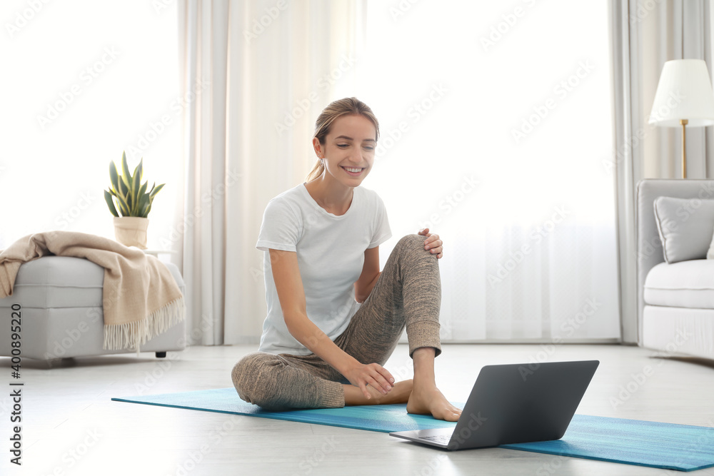 Woman having online video class via laptop at home. Distance yoga course during coronavirus pandemic Woman having online video class via laptop at home. Distance yoga course during coronavirus pandemic