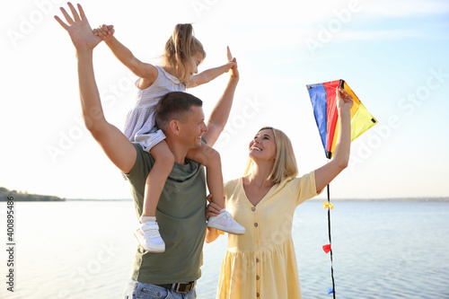 Happy parents with their child playing with kite on beach. Spending time in nature