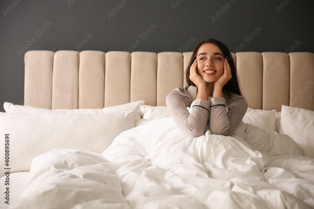 Beautiful young woman wrapped with soft blanket relaxing on bed at home Beautiful young woman wrapped with soft blanket relaxing on bed at home