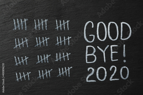 Crossed out sticks and text Goodbye 2020 on black chalkboard