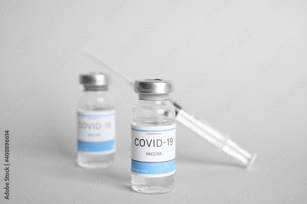 Vials with coronavirus vaccine and syringe on light background Vials with coronavirus vaccine and syringe on light background