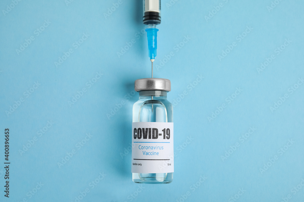Filling syringe with coronavirus vaccine on light blue background, flat lay Filling syringe with coronavirus vaccine on light blue background, flat lay