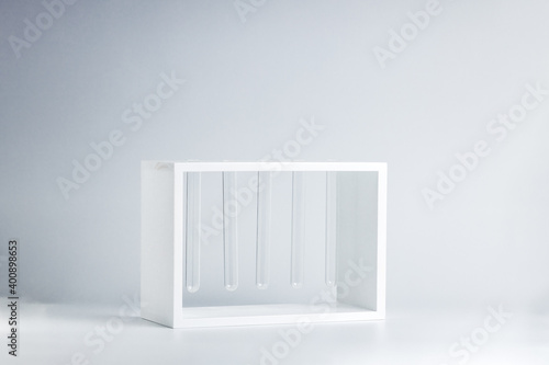 white flower vase made by glass test tubes stand over gray background. creative flowerpot