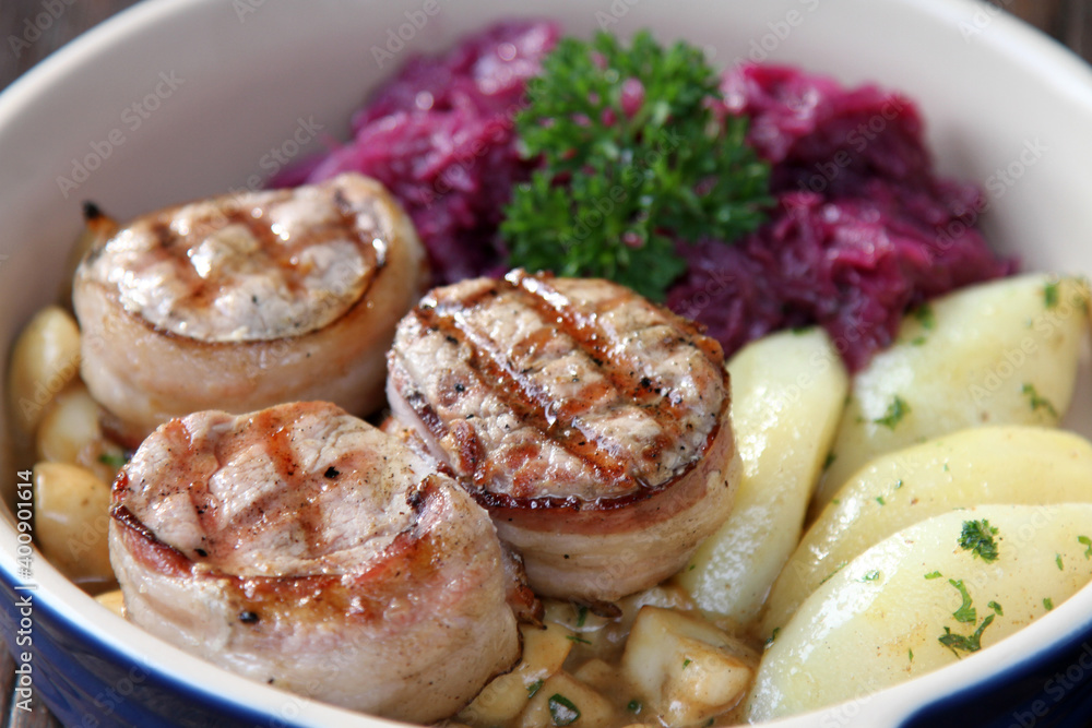 Pork medallions served with boiled potatoes. red cabbage and mushrooms