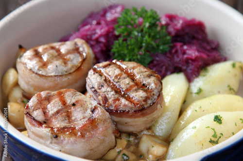 Pork medallions served with boiled potatoes. red cabbage and mushrooms