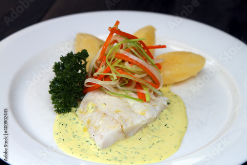 Photography Poached Hoki fish filled on mustard cream sauce, served with boiled potatoes