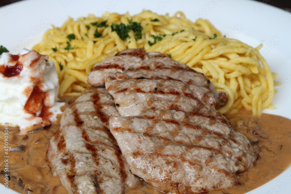 Pork escalope hunter style in creamy sauce served with spaetzle and whipped cream