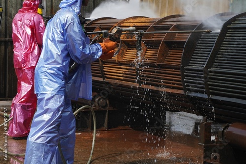 Worker use high pressure water jet to cleaning splashing the dirt of tube bundle in industrial areas, chemical products or oil and gas plants.