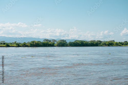 Magdalena River in Colombia, with blue sky and trees on the river bank.