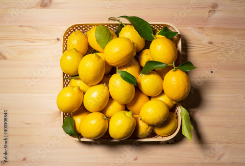 A lot of lemons in a basket on a wooden background