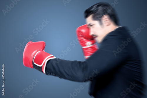 Asian businessman with red boxing gloves fighting