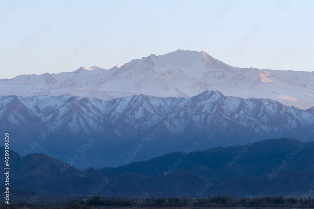 Naklejka premium Low contrast photo of mountain range with snow peaks in different shades of blue and cyan. Flat contrast scene with negative space available for text.