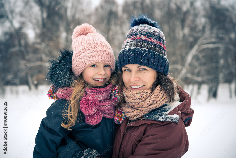 Fototapeta premium Little girl and her mother playing outdoors at winter day. Active winter holydays concept.