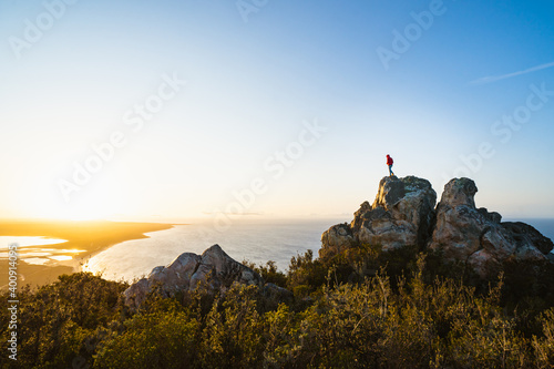 Lone man standing on the top of East Mount Barren as the sun rises behind him. Located in the Fitzgerald River National Park in Hopetoun, Western Australia.  photo