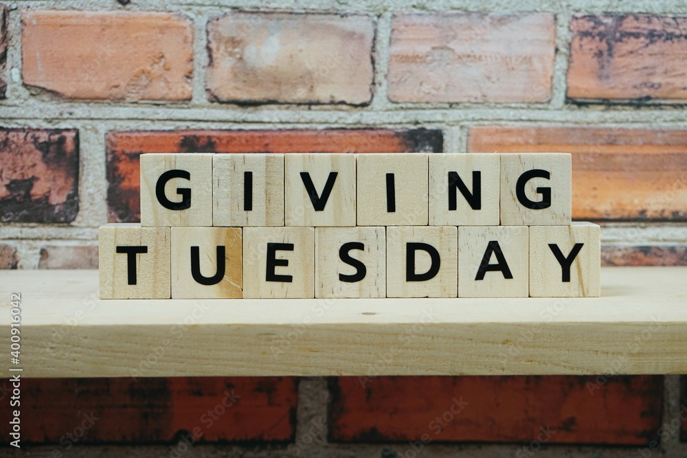 Naklejka premium Giving Tuesday alphabet letter on wooden shelves background