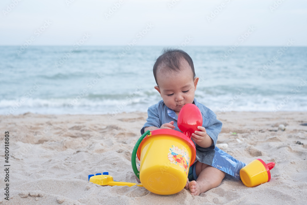 Adorable Cute Asian baby boy playing with beach toys on tropical beach Adorable Cute Asian baby boy playing with beach toys on tropical beach