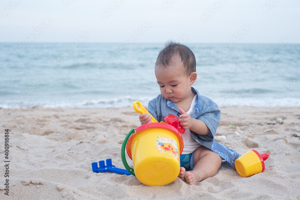 Adorable Cute Asian baby boy playing with beach toys on tropical beach Adorable Cute Asian baby boy playing with beach toys on tropical beach