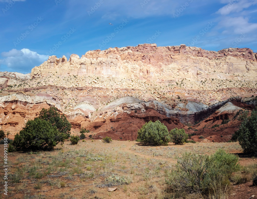 Unbelievable sandstone cliff and superlative domes with tumbleweeds on a hot summer partly cloudy day in Capitol Reef National Park in Southern Utah