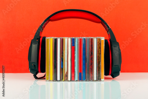 Headphones on a stack of CDs on a red background.