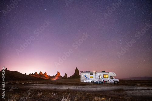 Camper rests under stars with campfire burning deep in background