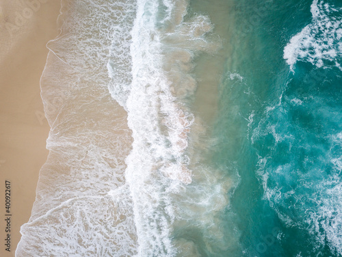 Aerial drone photo of beach in Australia with Pacific Ocean waves crashing in and golden sand beaches with blue water